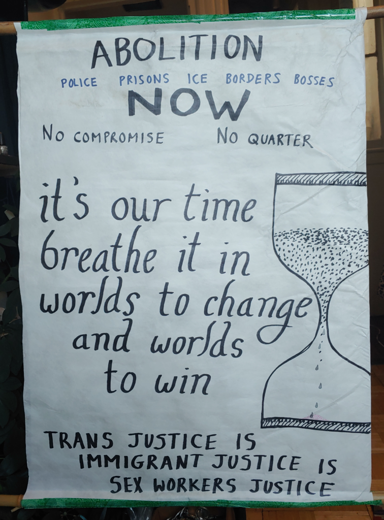 banner reading "abolition / police prisons ICE borders bosses / now / no conpromise, no quarter", "it's our time, breathe it in, worlds to change and worlds to win" alongside an hourglass, "trans justice is immigrant justice is sex workers justice"